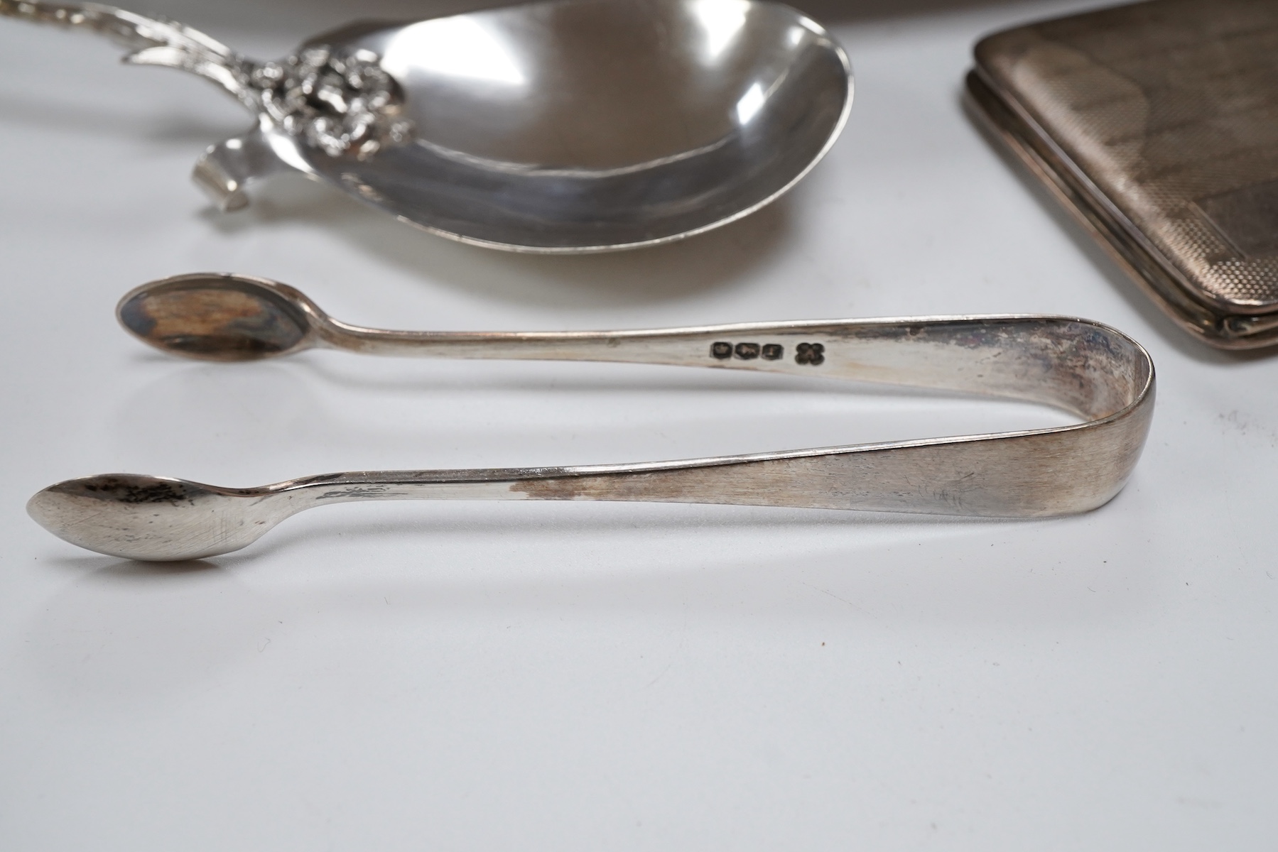 A Victorian silver bun salt, London, 1860, a later silver cigarette case, a silver napkin ring and pair of silver sugar tongs, together with a continental white metal serving spoon and a silver plated oval tray.
